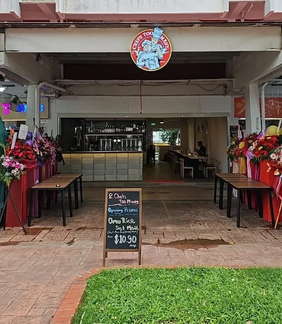2 Chefs Too Many storefront under an HDB block in Changi Village, with opening-day flower stands